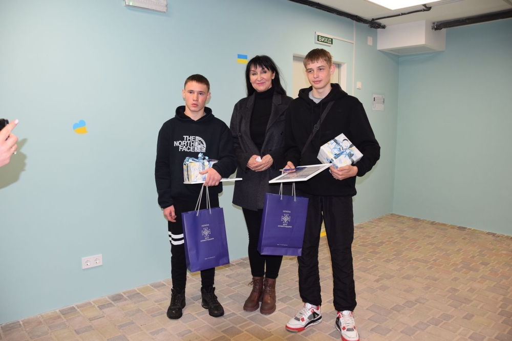 Двоє хлопців з грамотами та жінка стоять у Петрівському ліцеї