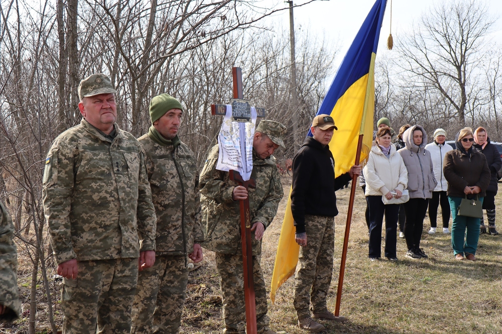 Воїн тримає намогильний хрест загиблого Віктора Гнідікова