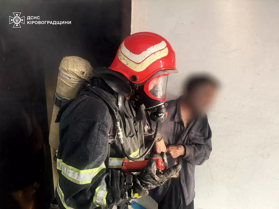 Рятувальник виводить чоловіка з квартири де сталася пожежа