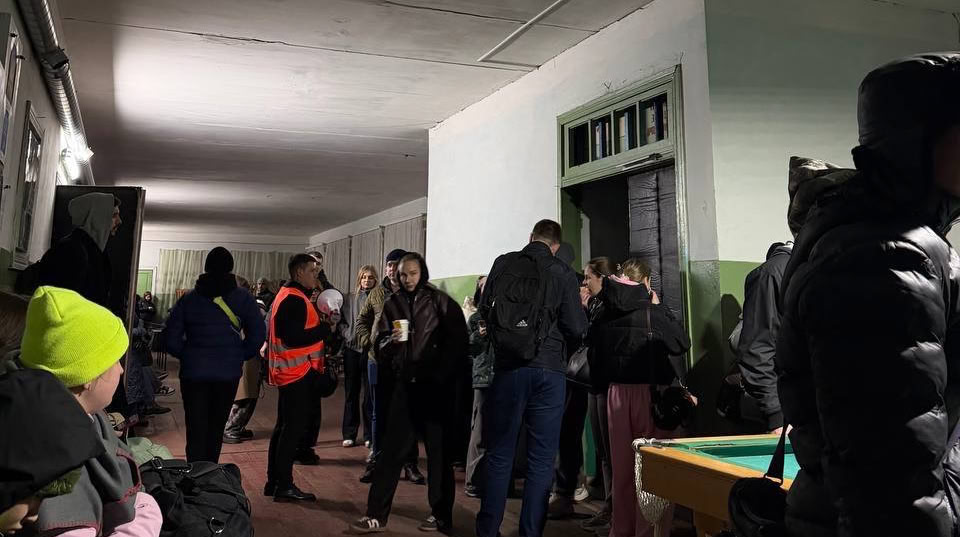 Евакуйовані з поїзда люди стоять у приміщенні