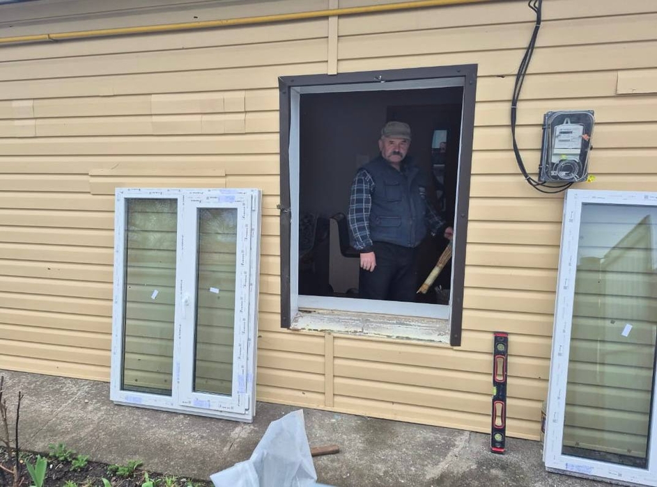 Чоловік встановлює вікно в будинку