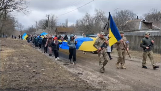 Люди несуть прапор під час прощання з Сергієм Шкутенком