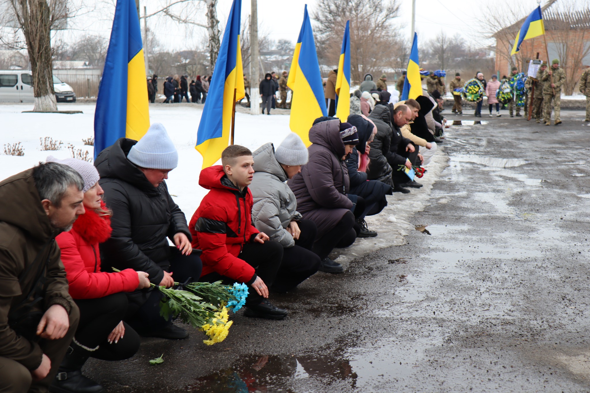 Люди стоять на колінах на прощанні з Миколою Сичовим з Онуфріївської громади