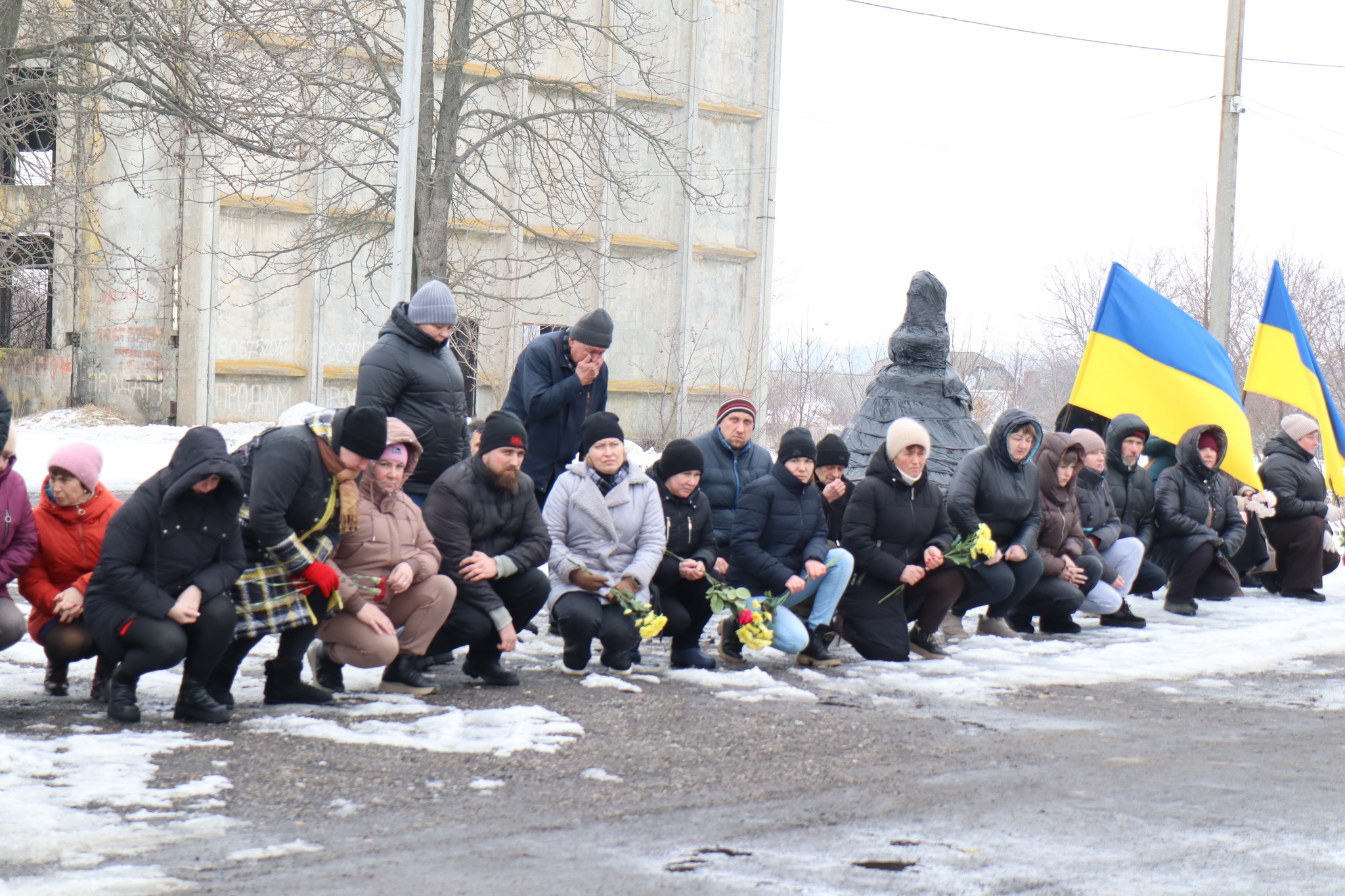 Люди стоять на колінах на прощанні з Миколою Сичовим з Онуфріївської громади