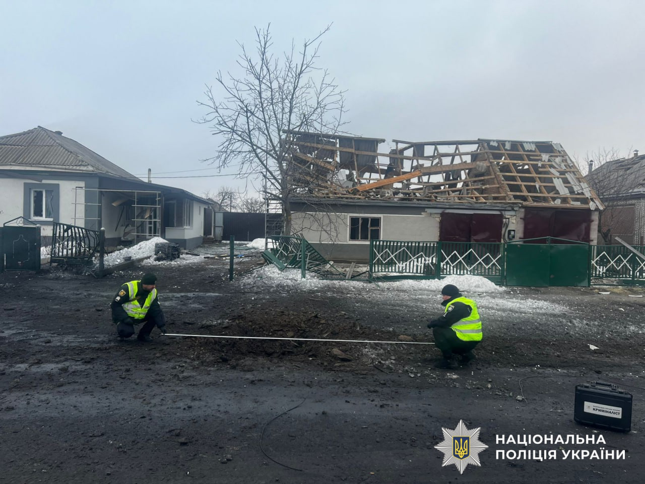 Правоохоронці вимірюють довжину вирви після російського обстрілу