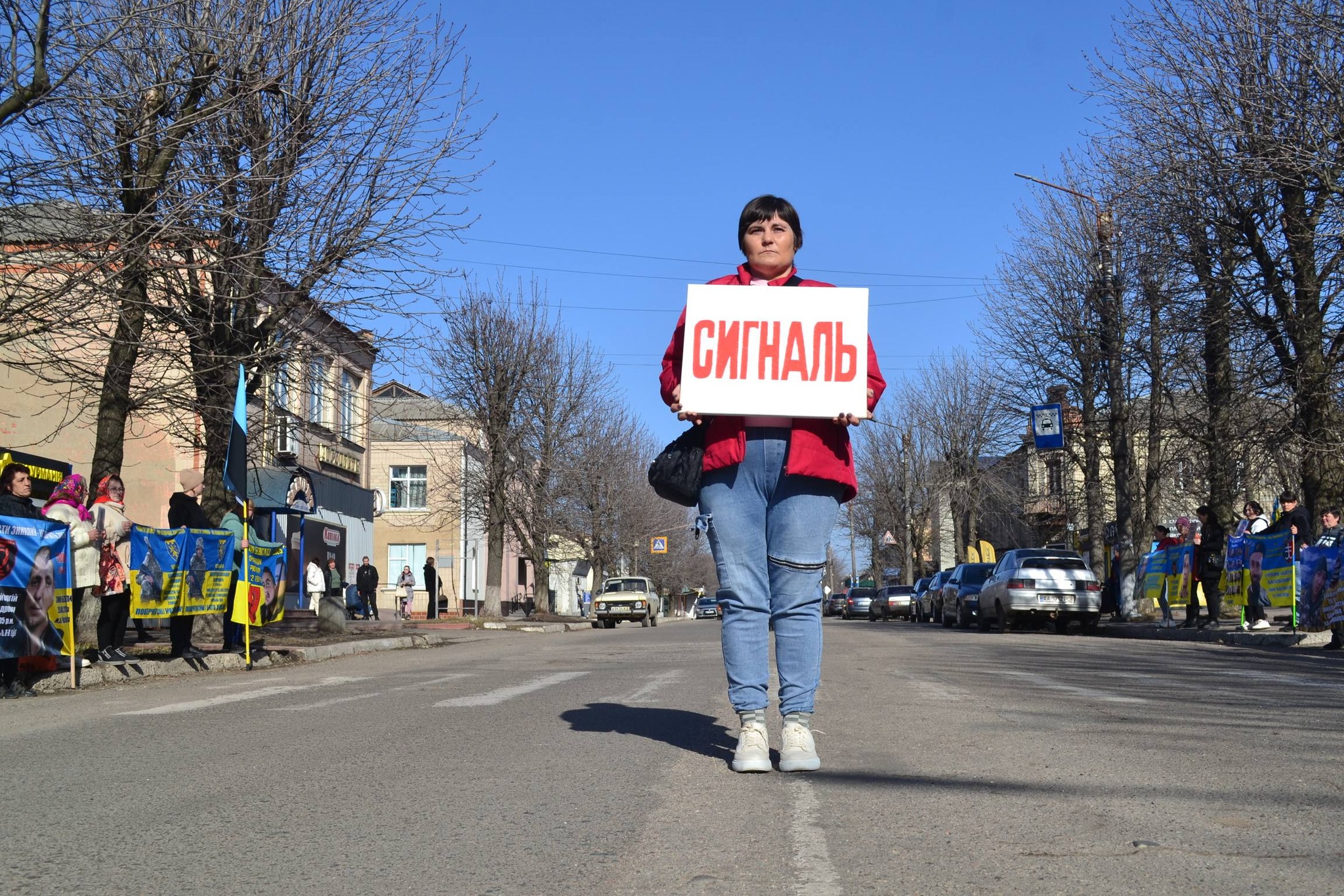 Жінка стоїть з табличкою, на якій написано "Сигналь"