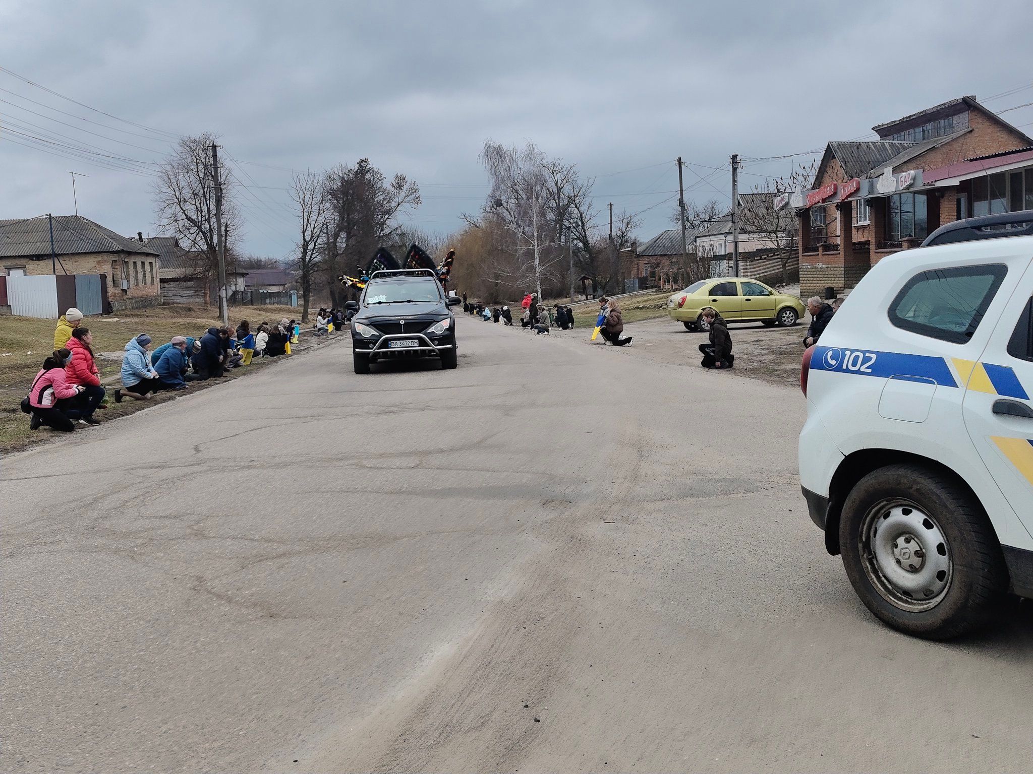 Люди на колінах зустрічають траурний кортеж загиблого Олександра Середи