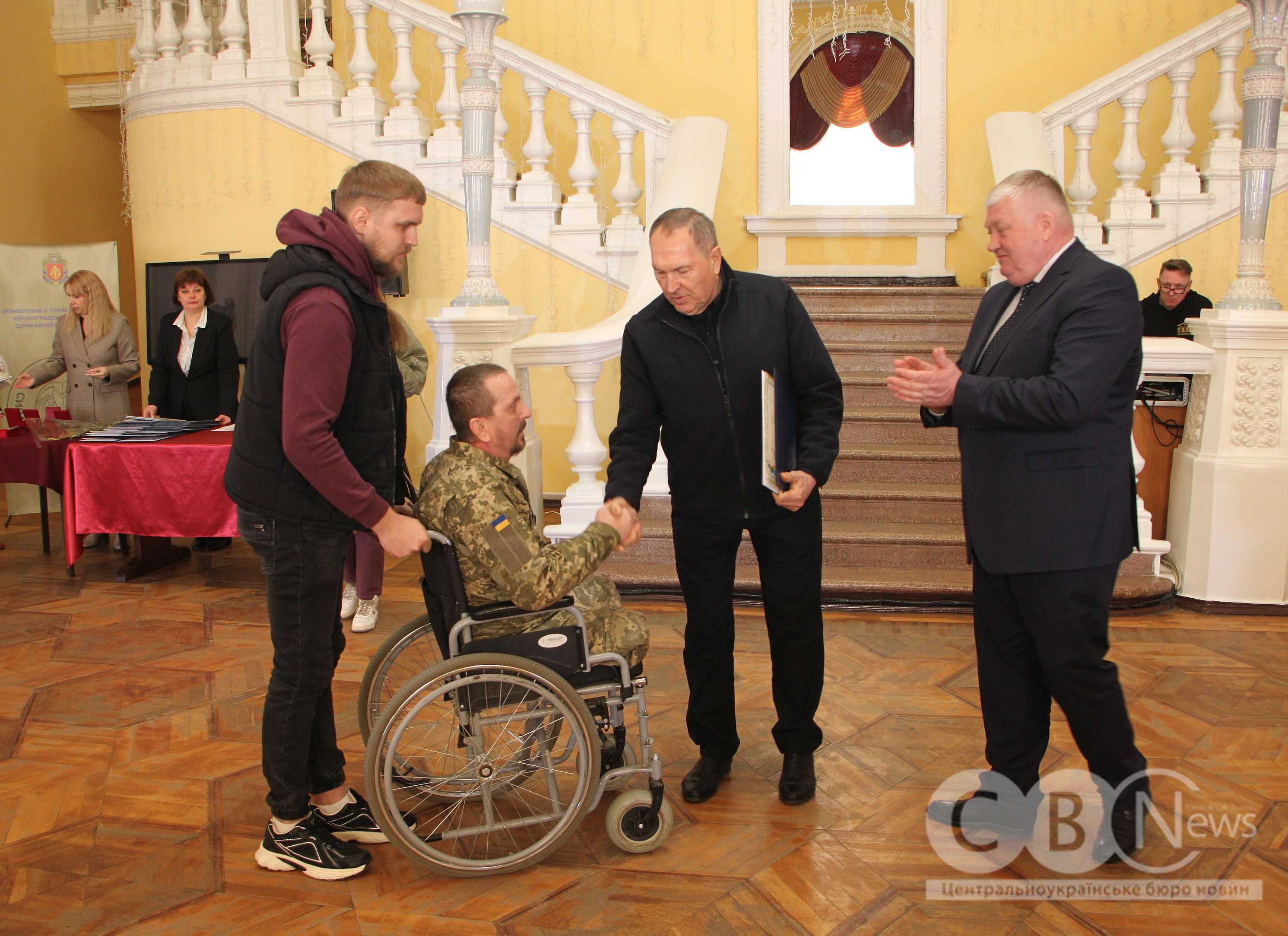 Андрій Райкович тисне руку ветерану на кріслі колісному