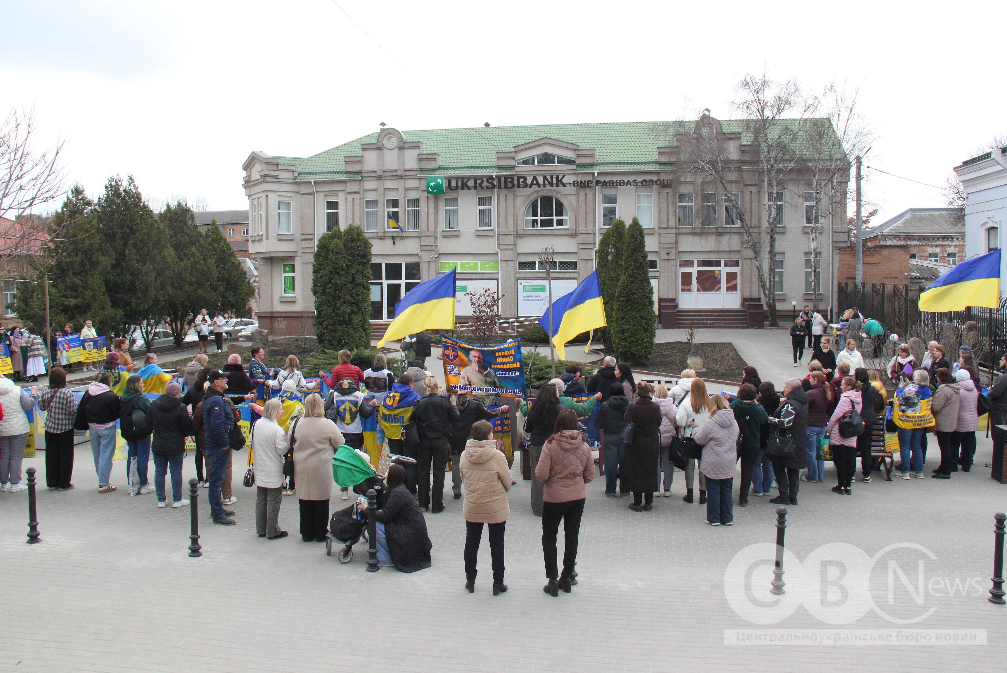 Люди з плакатами та прапорами зібралися на відкриття інсталяції