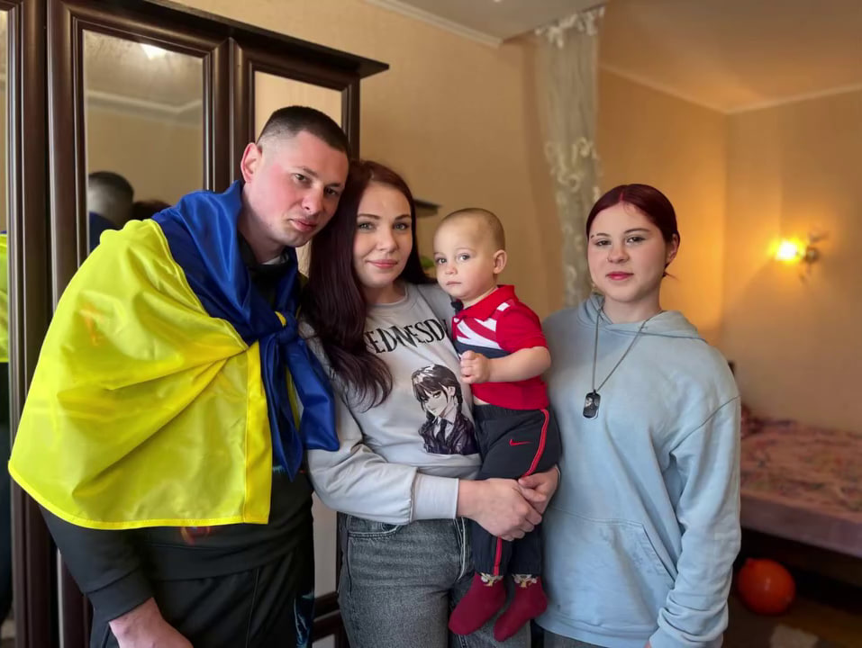 Звільнений з полону воїн стоїть поруч з родиною