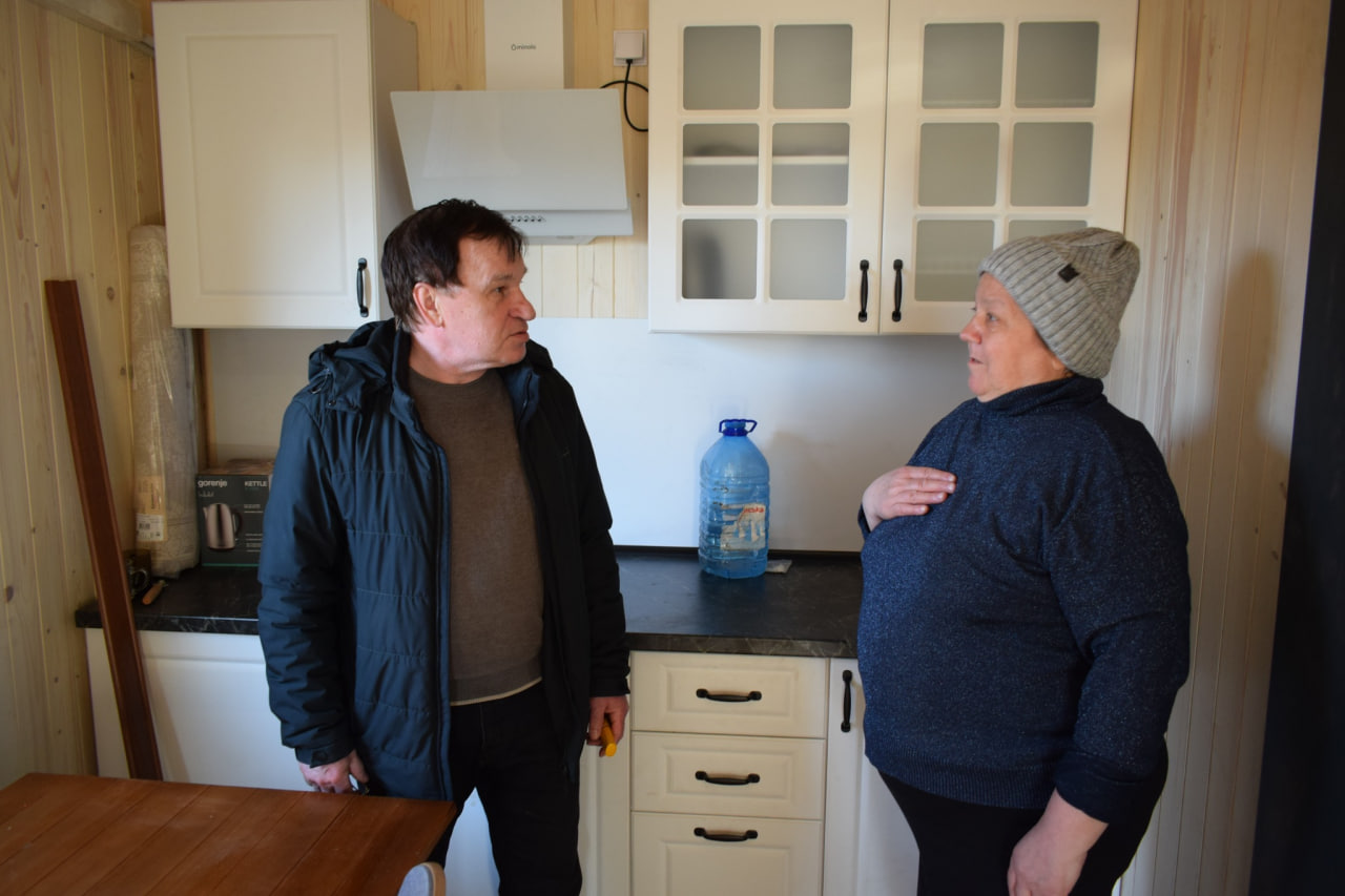 Люди на кухні модульного житла під час передачі будинку родині