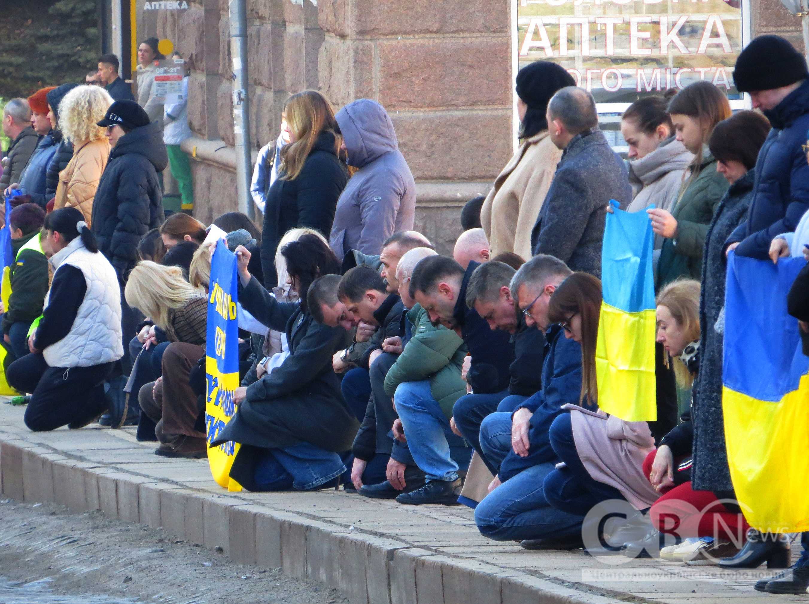 Кропивничани з прапорами стоять на колінах під час прощання із загиблими воїнами