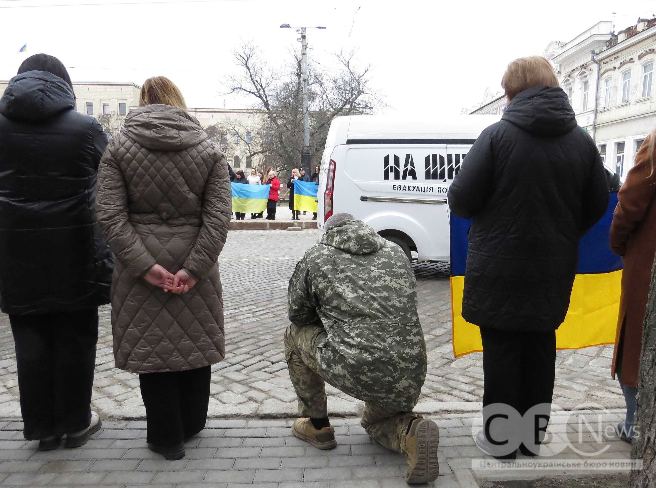 Фото людей зі спини, які вшановують загиблих військових на прощанні