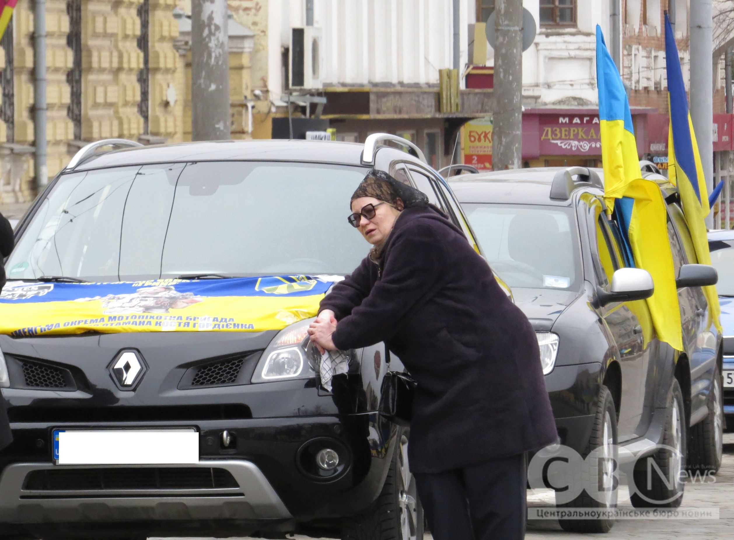 Жінка схилились на капот автівки з портретом загиблого військового