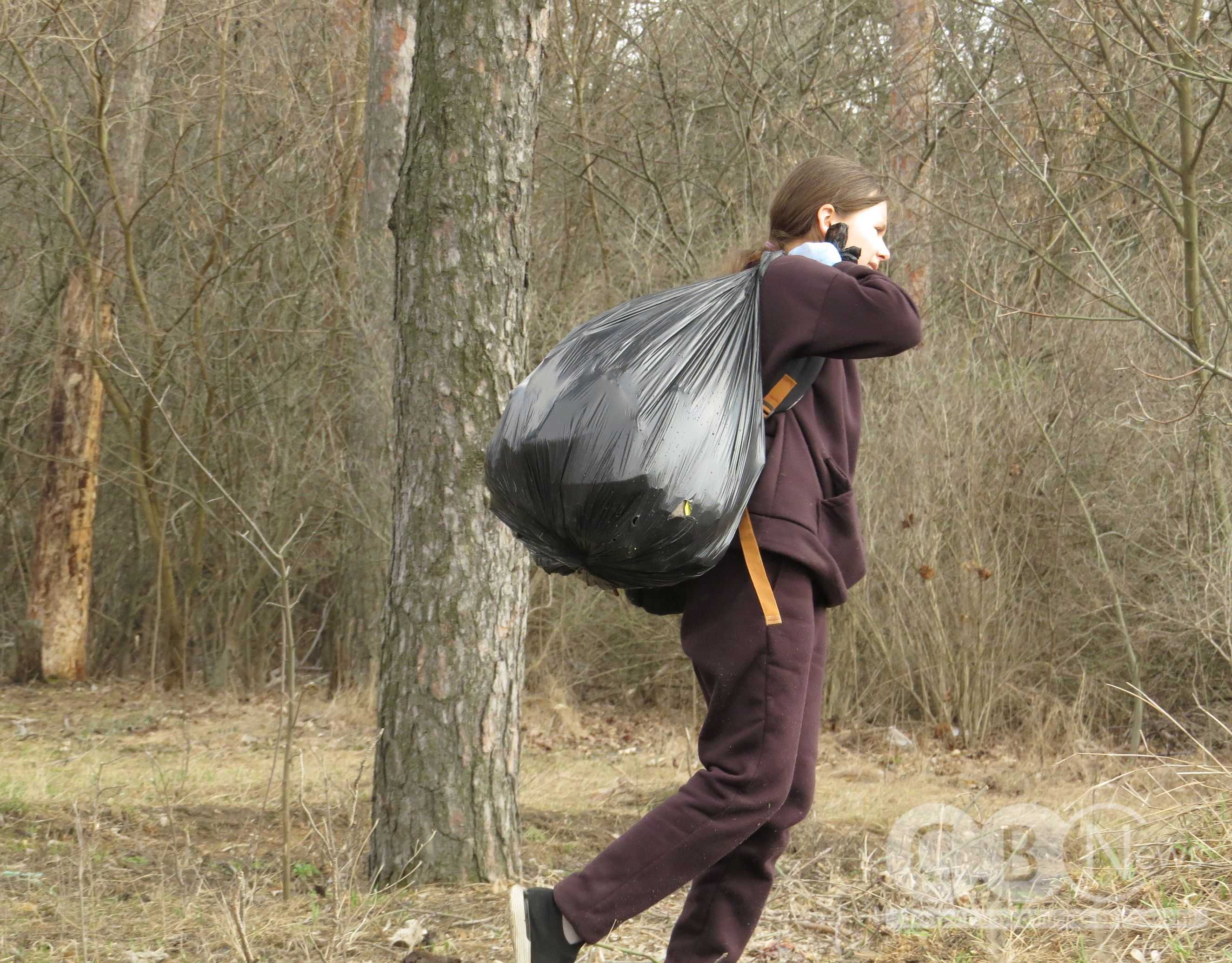 Дівчинка несе повний пакет сміття