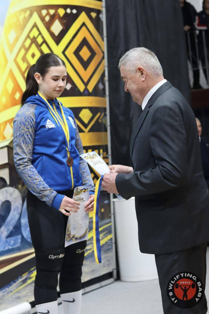 Чоловік вручає грамоту кропивницькій важкоатлетці