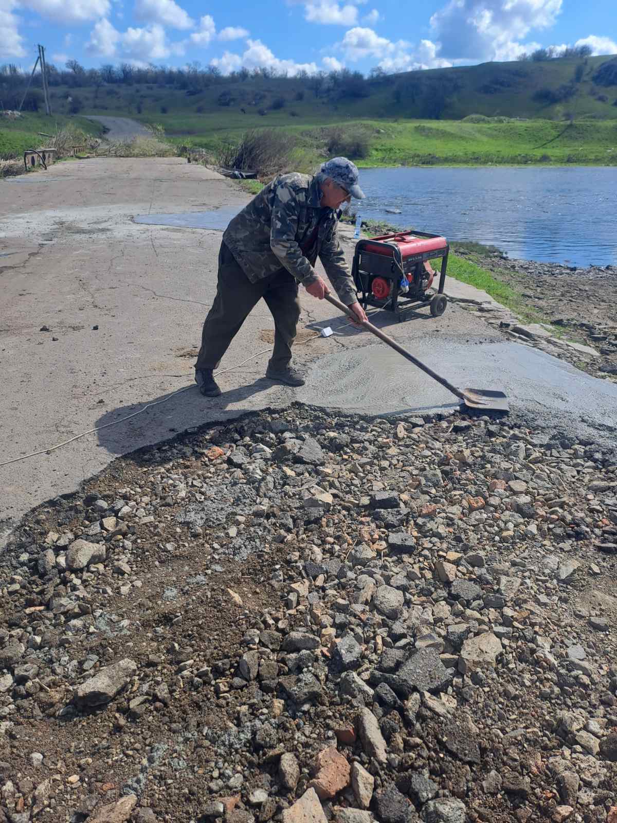Комунальник засипає яму, яка утворилася на аварійному мосту в Устинівській громаді
