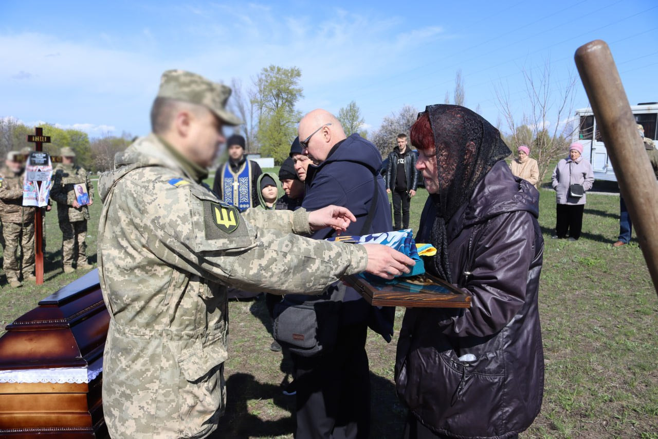 Військовий передає рідним загиблого прапор