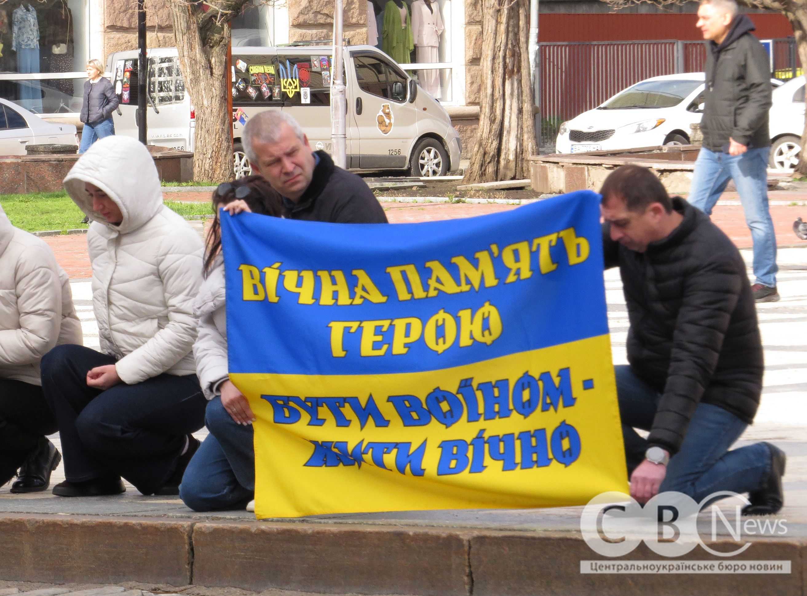 Люди стоять на колінах під час прощання з воїнами з Кропивницького