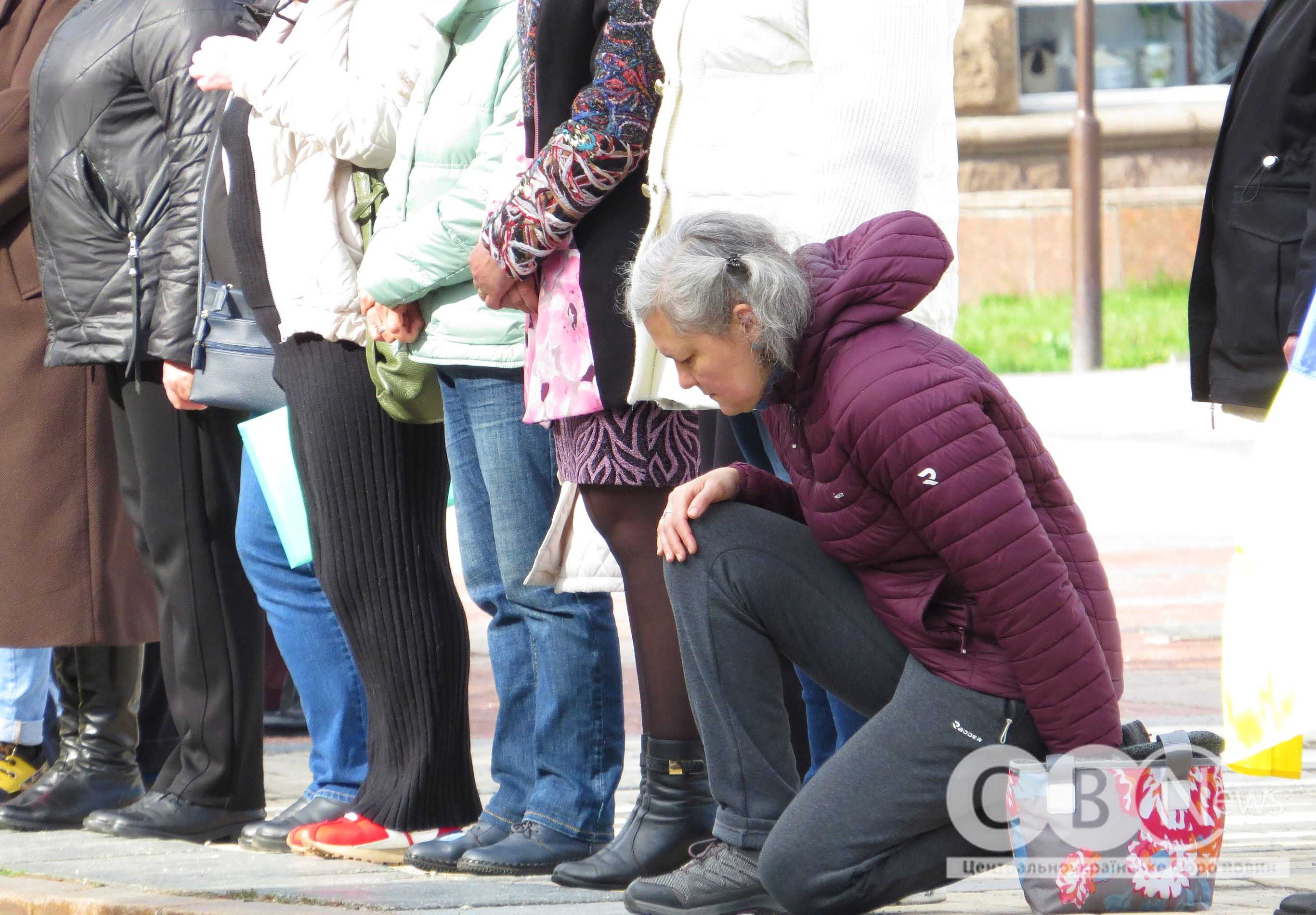 Жінка стоїть на колінах під час прощання з воїнами з Кропивницького